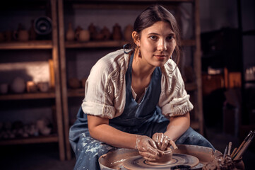Stylish female master works with clay on a potter's wheel. Restoration of forgotten pottery traditions.