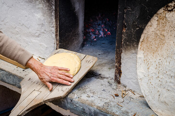 Woman baking homade bread in traditional oven. Rhodes, Archangelos, Greece.