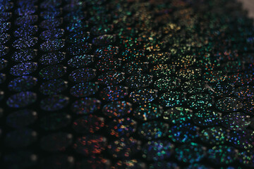 Sequins close-up macro. Abstract background with blue sequins and lilac color on the fabric....