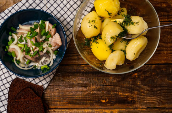 rustic dinner, boiled potatoes with herbs, herring and black bread on an old wooden table, space koria