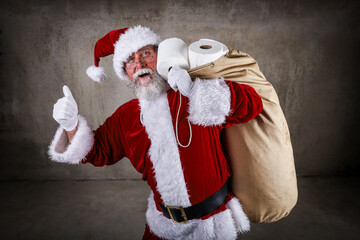 Santa Claus holding a sack full of toilet paper and giving the thumbs up sign during pandemic