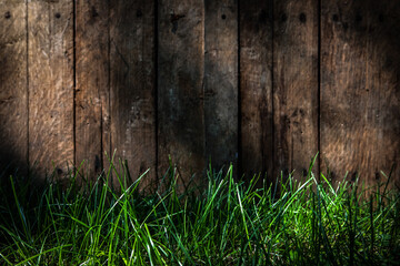 Old wooden wall background with long green grass in foreground