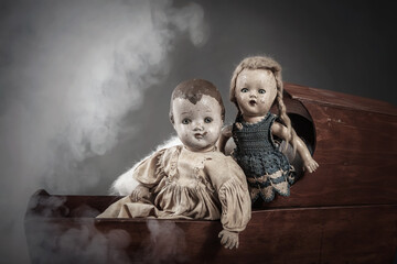 Scary abandoned old baby dolls in a cradle with misty smoke