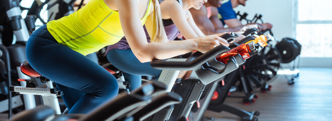 Caucasian woman and her friends on fitness bike in gym