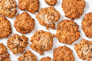 Lots of homemade oatmeal cookies with a various nuts and sesame seeds on a white background top view. Oatmeal cookies background.