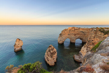 Naklejka premium Algarve in Portugal and its amazing beaches, is a summer holiday destination for many tourists in Europe. Landscape with cliffs on the coast at colorful sunset. Pure nature, blue sea, sand.