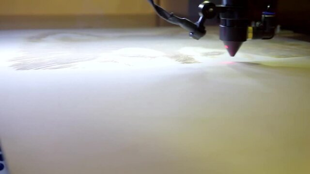Laser engraving on wood. Laser printer moves on a wooden surface.
