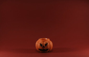 One scary orange pumpkin shaped candle, isolated on red background, space for text. Tradition Happy Halloween concept.
