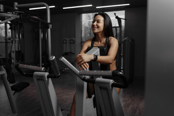 Fototapeta na wymiar Happy fitness woman resting after training in the gym. Mirror view of young sporty girl laughing during a break after training. Fitness and sports concept