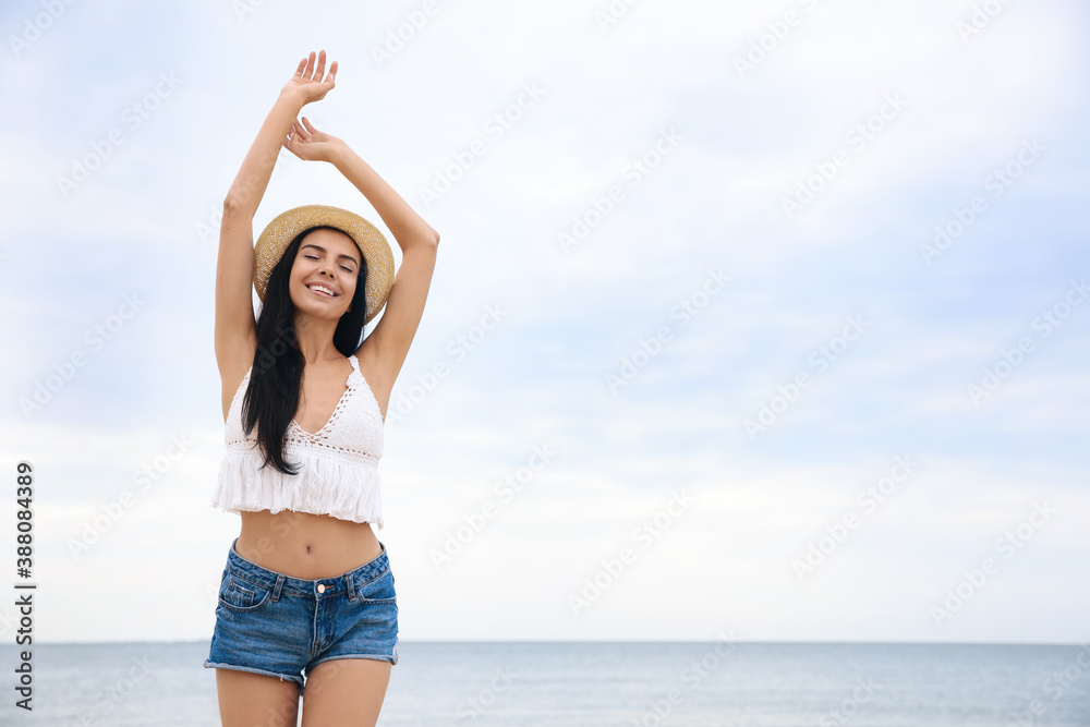 Poster Beautiful young woman with beach hat near sea. Space for text