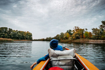Evening kayak trip along the river in autumn. The active lifestyle of the child in the family.
