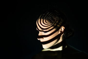 Portrait of a woman illuminated with a projected light in a spiral shape.