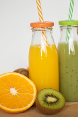 botellas de zumo de naranja y kiwi con fruta partida alrededor