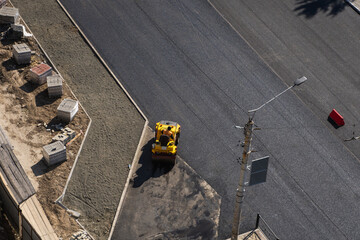 Little asphalt road roller with heavy vibration roller compactor press new hot asphalt on the roadway on a road construction site. Heavy Vibration roller at asphalt pavement working. Repairing.