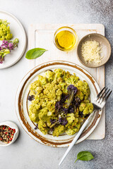 Fried green and purple cauliflower with herbs and spices on plate over gray stone background. Top view