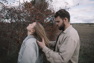 a couple in love walks in an open soybean field in the evening in cloudy weather