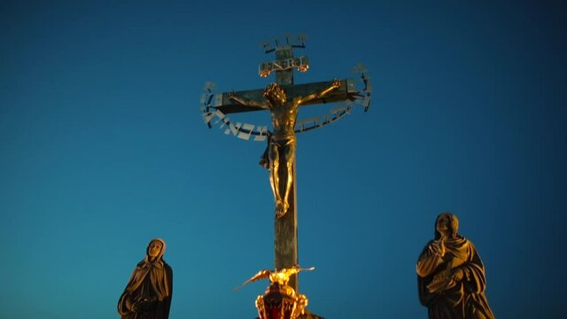 A crucifix is an image of Jesus on the cross illuminated by a golden glow against the background of a dark sky. A part of one of the most historically interesting sculptures on the Charles bridge.