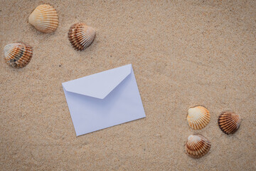 Arrière-plan grains de sable de mer, sable fin de plage avec enveloppe et coquillages. Emplacement pour texte sur papier.