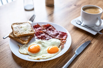 Tasty breakfast with two eggs, bacon, toasts and coffee