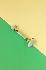 Green Gua Sha facial massage tools. Green Quartz jade roller on yellow background. Anti age,...