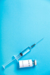 On a blue background, a syringe and a vial with a vaccine against the virus.