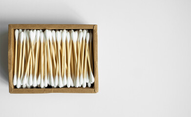 Eco-friendly cotton swabs. A cardboard box containing recyclable bamboo cotton buds on a gray surface. Zero waste concept. Eco product. Cosmetic sticks in a box. Wooden sticks for cleaning ears.
