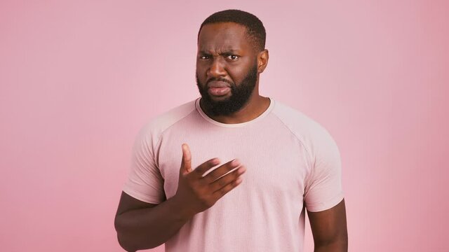 Its not me. Confused african american guy raising his hands and shaking head no, pink studio background