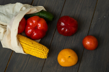 Zero waste concept. Pepper, tomato, corn, cucumber in reusable shopping eco friendly cotton fabric bags. Vegetables in eco bag on a wooden table. Plastic free concept.