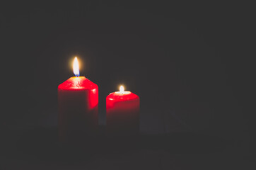 two red candles burning on black background