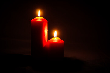 two red candles burning on black background