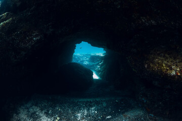 Underwater scene with tunnel cave in sea. Dive site for divers and freedivers