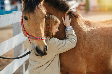 Friendship of a little ginger girl and her horse. Touching and leaning