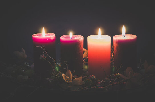 four  advent candles burning on black background