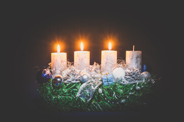 three advent candles burning on black background