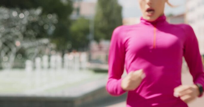 Young sporty woman jogging in city park , stop for breathing near fountain and keep running, slow motion
