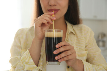 Young woman with cold kvass indoors, closeup. Traditional Russian summer drink