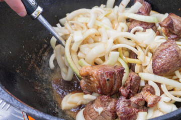 Cooking pilaf in a cauldron on the grill outside in the summer