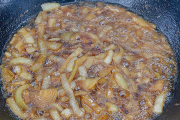 Cooking pilaf in a cauldron on the grill outside in the summer