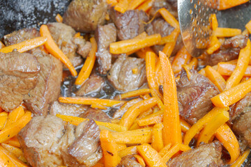 Cooking pilaf in a cauldron on the grill outside in the summer