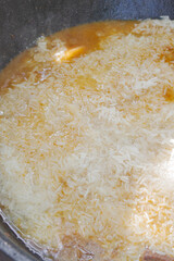 Cooking pilaf in a cauldron on the grill outside in the summer
