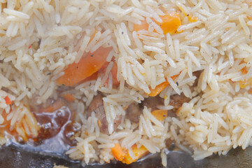 Cooking pilaf in a cauldron on the grill outside in the summer