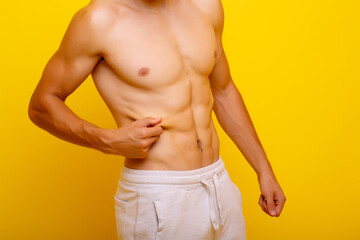 Obraz premium Cropped photo of muscular man with six pack abs isolated on yellow background. Fitness motivation, workout sport motivation.