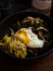 Poached egg and fermented vegetables in black bowl