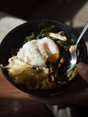 Poached egg and fermented vegetables in black bowl
