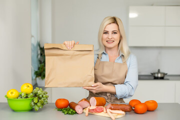 Self Isolation Concept. woman unpacking paper bag with food in kitchen, ready for quarantine during epidemic outbreak