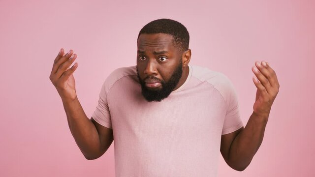 African american man raising his hands, waiting for excusement, pink studio background
