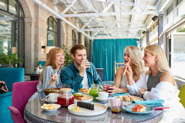 cheerful caucasian friends spending time together in bright cozy time cafe, they have fun, talk, chatting. lunch time or they celebrating something, entertaining