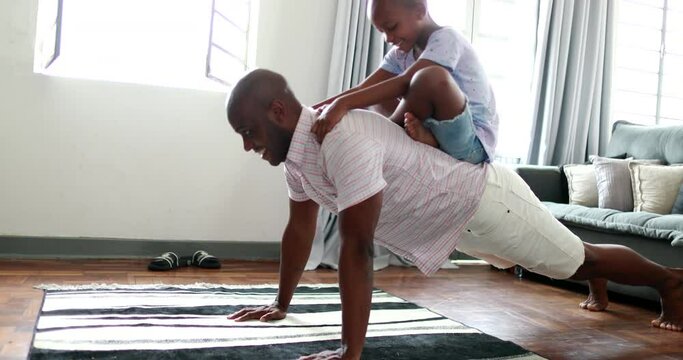 Father and child bonding together, dad doing push-ups with son in back