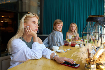 young bored caucasian woman sits alone at restaurant, she is waiting someone for date, look away