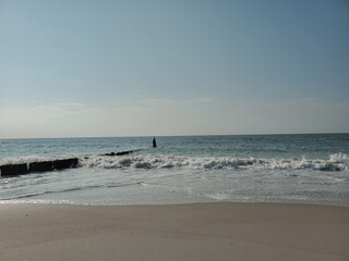 Fototapeta na wymiar City Beach, Rockaway beach, quiet and empty ocean with a peaceful glow in the background. New York